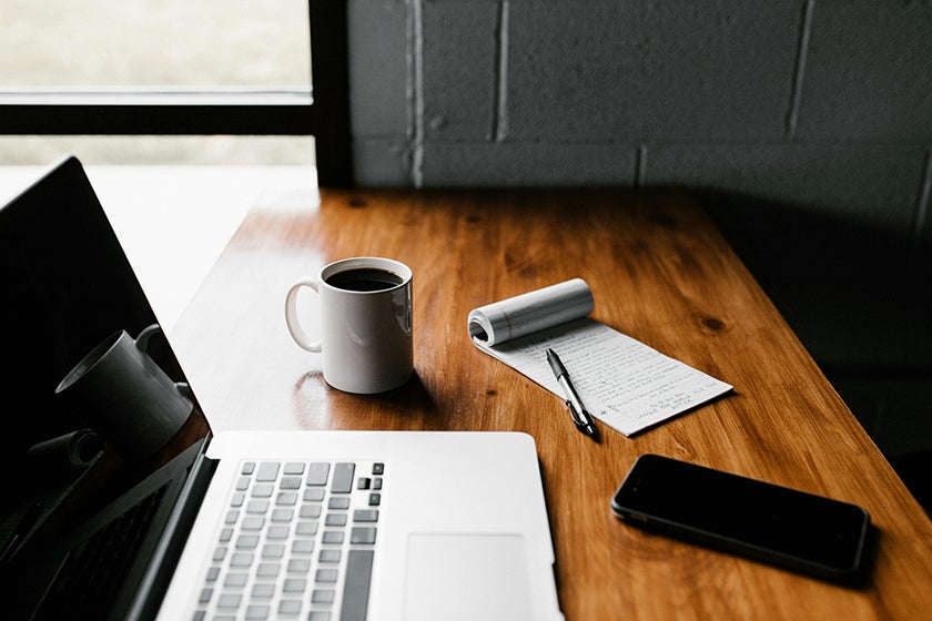open laptop on a desk with a coffee cup